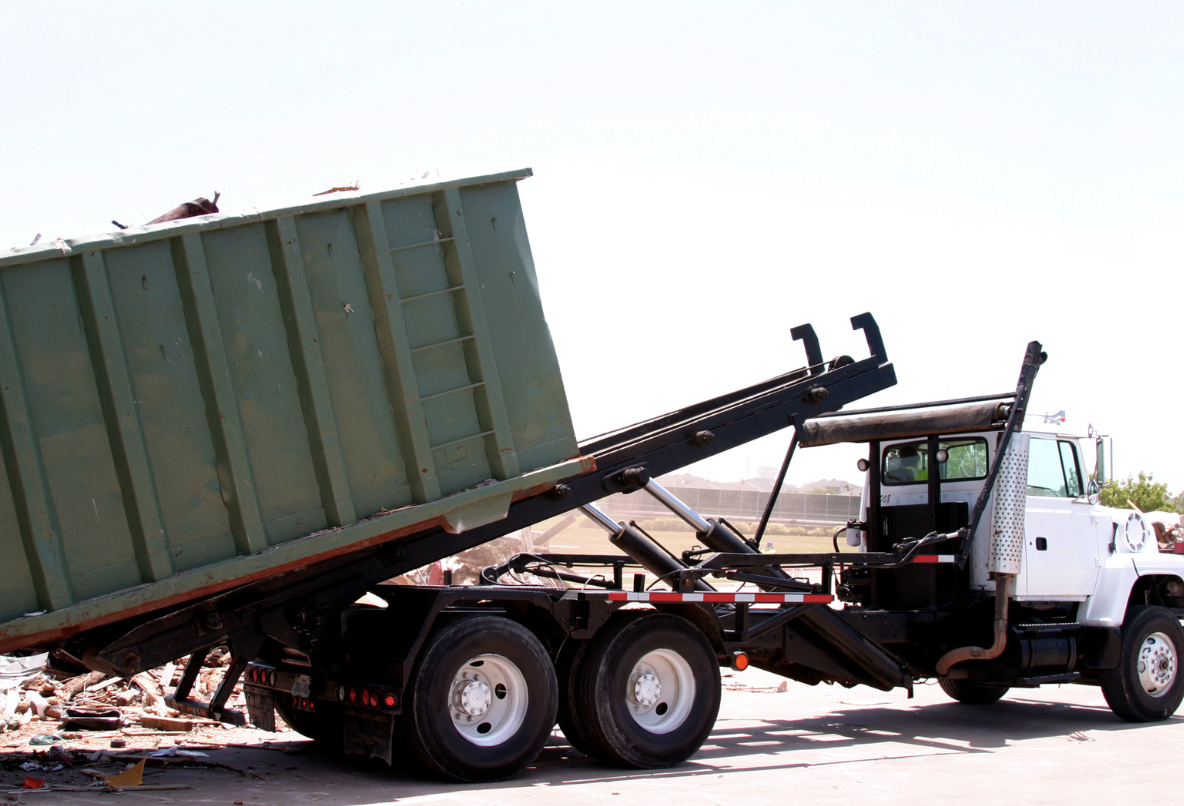 Roll-off truck tipping a dumpster at a disposal site